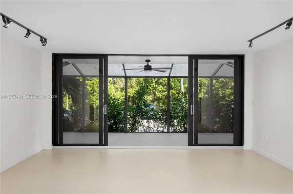an empty room with sliding glass door and garden