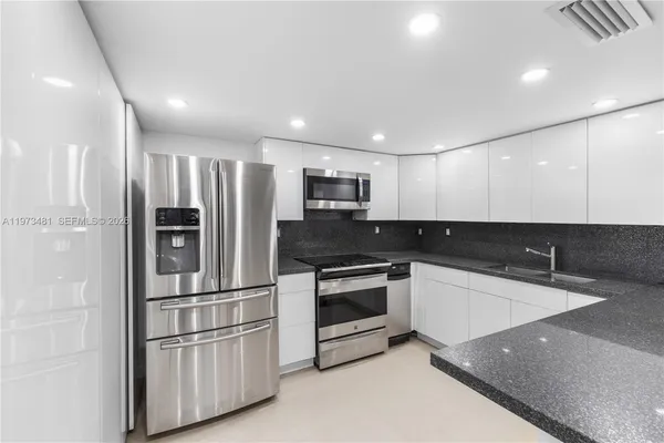 a kitchen with stainless steel appliances granite countertop a refrigerator and a stove top oven