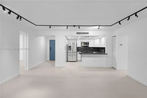 a view of a big room with stainless steel appliances kitchen island granite countertop a refrigerator and a sink