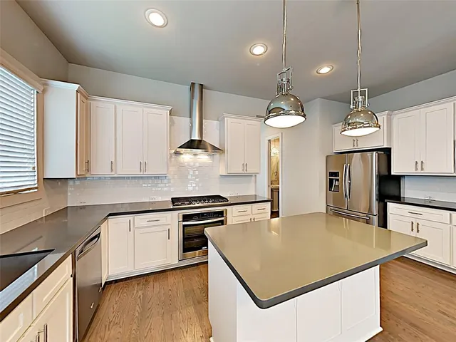 a kitchen with stainless steel appliances a stove a sink a center island and cabinets