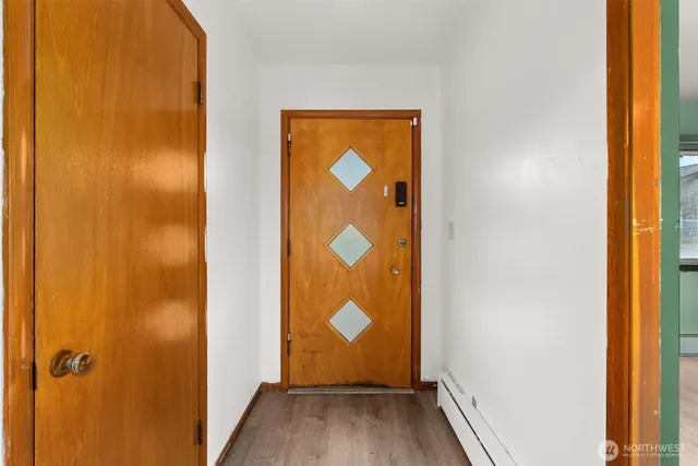 a view of an empty room with a window and wooden floor