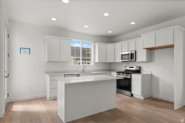 7797 West Alta Springs Way Magna, UT 84044 - Photo 11 of 21 Kitchen featuring appliances with stainless steel finishes, white cabinets, light wood finished floors, recessed lighting, and a center island
