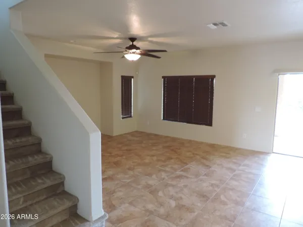 a view of an empty room with stairs and a chandelier fan