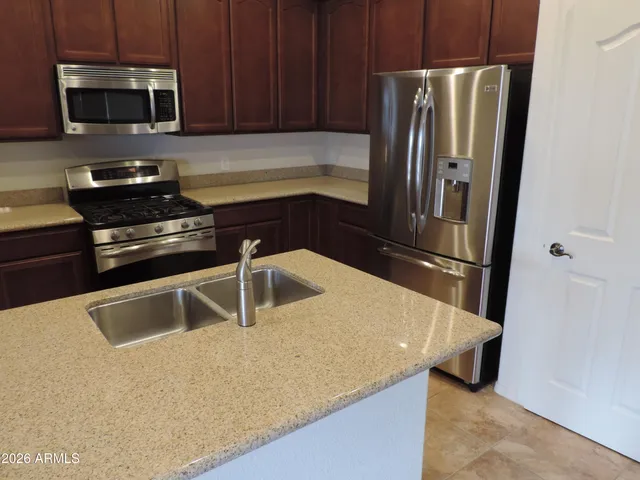 a kitchen with stainless steel appliances granite countertop a refrigerator a stove and a sink with wooden floor