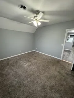 an empty room with a chandelier fan and windows