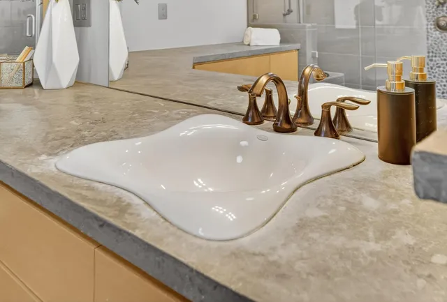 a bathroom with a granite countertop double vanity sink a mirror and a shower