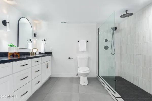 a bathroom with a granite countertop sink a toilet and a mirror