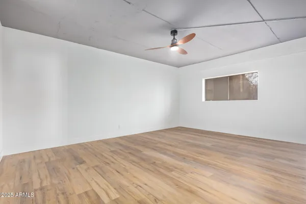 an empty room with wooden floor and ceiling fan