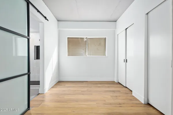 a view of an empty room with wooden floor and a window