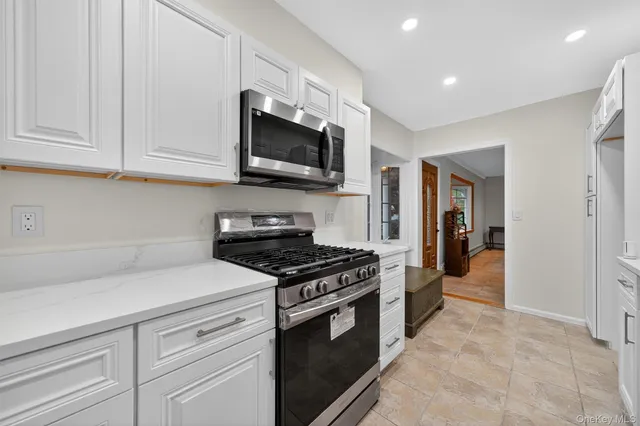a kitchen with stainless steel appliances granite countertop grey cabinets a stove top oven and sink