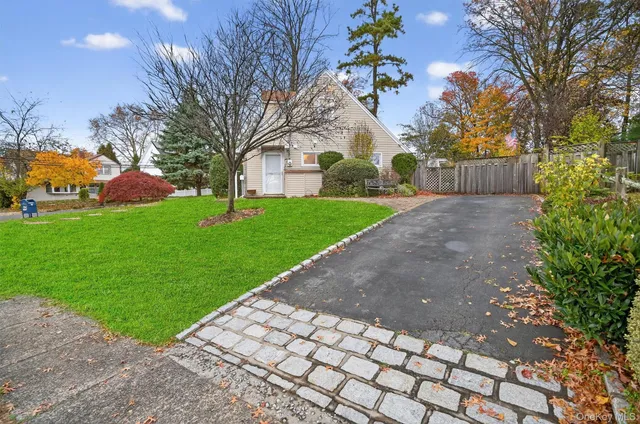 a view of a white house with a yard and large tree