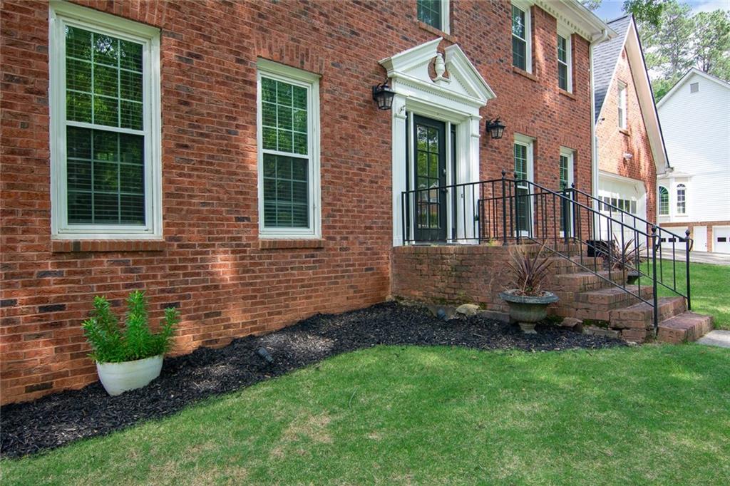 a view of a brick house with a yard and plants