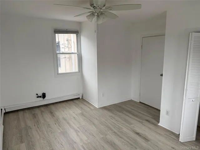 an empty room with wooden floor closet and windows