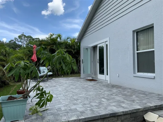 a view of yellow house with potted plants in front of door