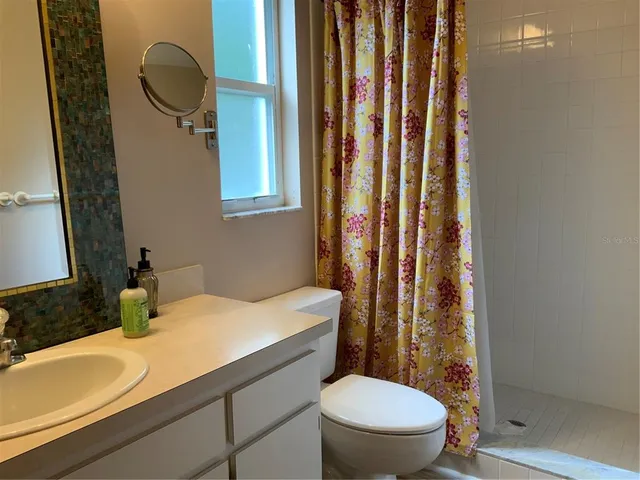 a bathroom with a granite countertop toilet sink and mirror