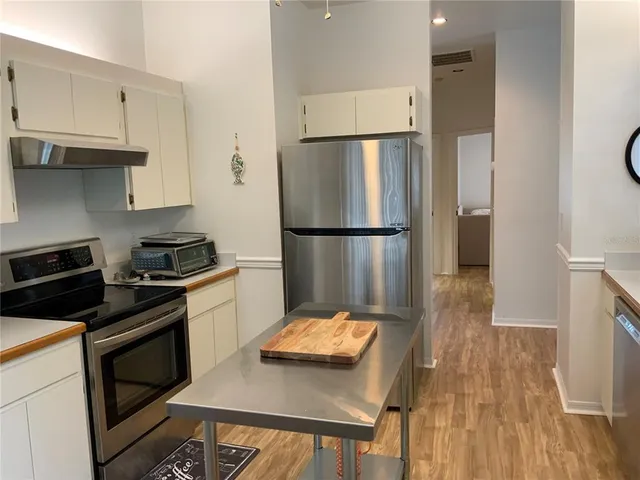 a kitchen with a refrigerator stove and wooden floor