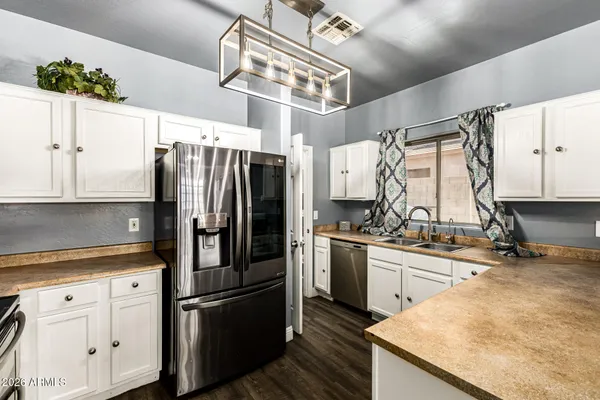 a kitchen with stainless steel appliances granite countertop a refrigerator a sink dishwasher a stove and white cabinets with wooden floor