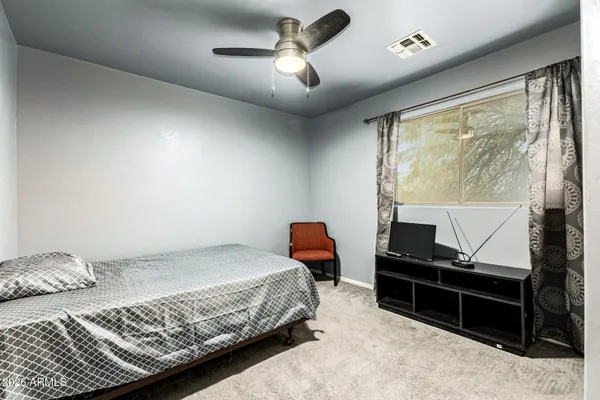 a bedroom with a bed and a flat tv screen on dresser