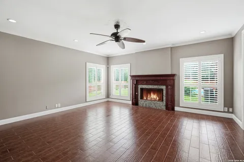 a view of an empty room with wooden floor fireplace and a window