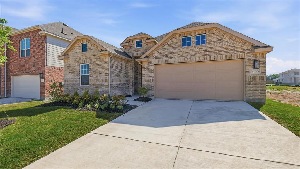 2529 Rivers W Road Anna, TX 75409 - Photo 4 of 40 Light brick exterior with contrasting dark trim, featuring a two-car garage