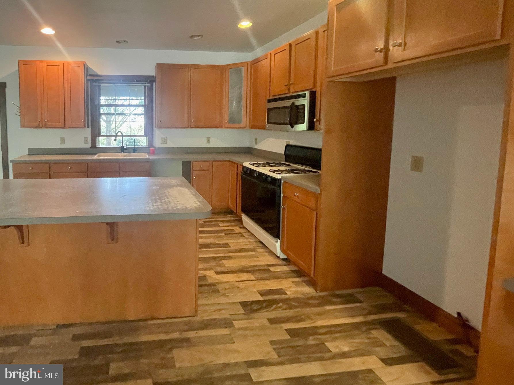 279 Esbenshade Road Ronks, PA 17572 - Photo 8 of 24 a kitchen with kitchen island granite countertop wooden cabinets a sink a stove a refrigerator and a microwave