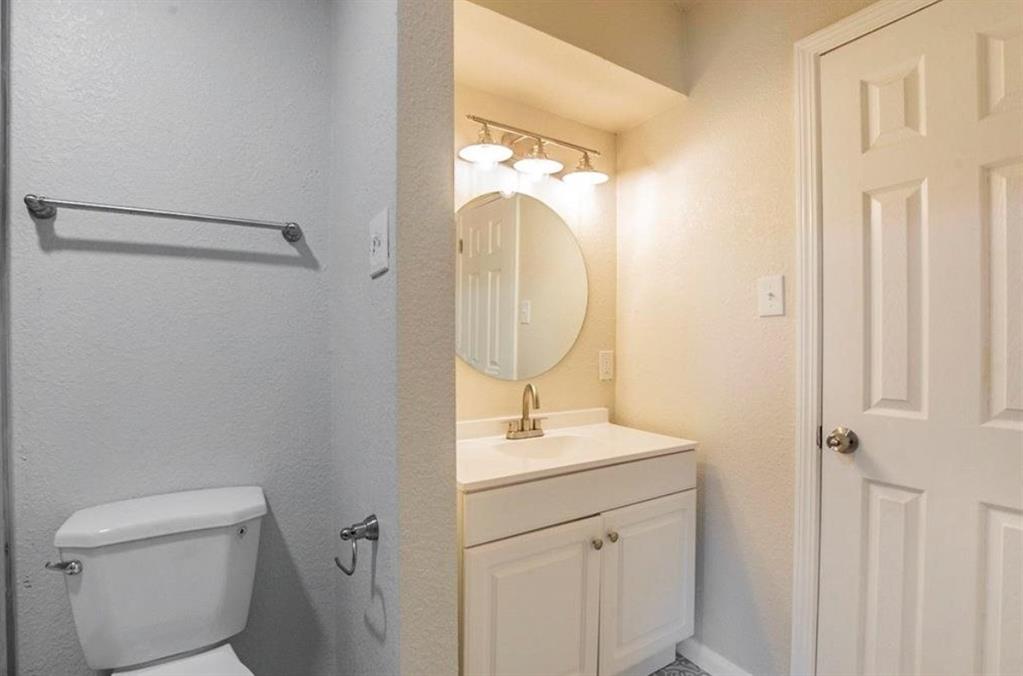 1821 East Grauwyler Road, Unit 188 Irving, TX 75061 - Photo 12 of 20 Bathroom vanity featuring a circular mirror, brushed gold-tone faucet, and white cabinetry