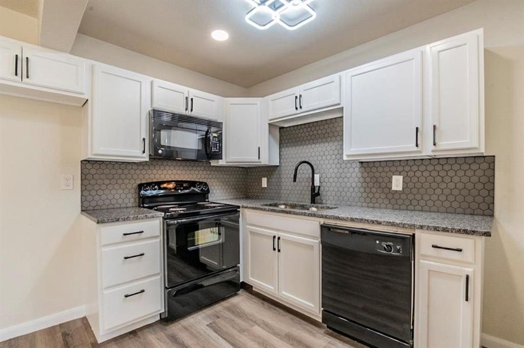 1821 East Grauwyler Road, Unit 188 Irving, TX 75061 - Photo 2 of 20 Modern kitchen featuring white shaker cabinetry, dark countertop surfaces, a hexagonal tile backsplash, a black appliance suite, and wood-finish flooring
