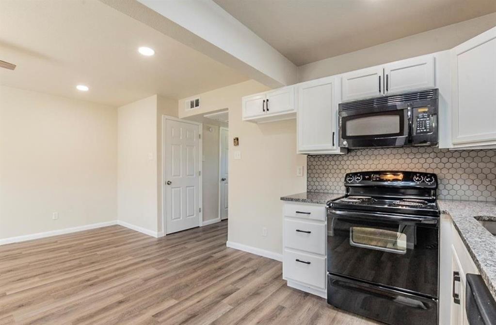 1821 East Grauwyler Road, Unit 188 Irving, TX 75061 - Photo 3 of 20 Kitchen area with white cabinetry, black appliances, light-toned wood-finish flooring, and a hexagonal tile backsplash
