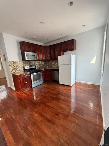 a kitchen with stainless steel appliances wooden floors and wooden cabinets