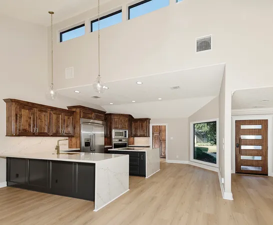 a kitchen with stainless steel appliances kitchen island granite countertop a refrigerator and a sink
