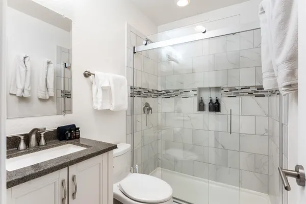 a bathroom with a granite countertop sink a toilet and shower