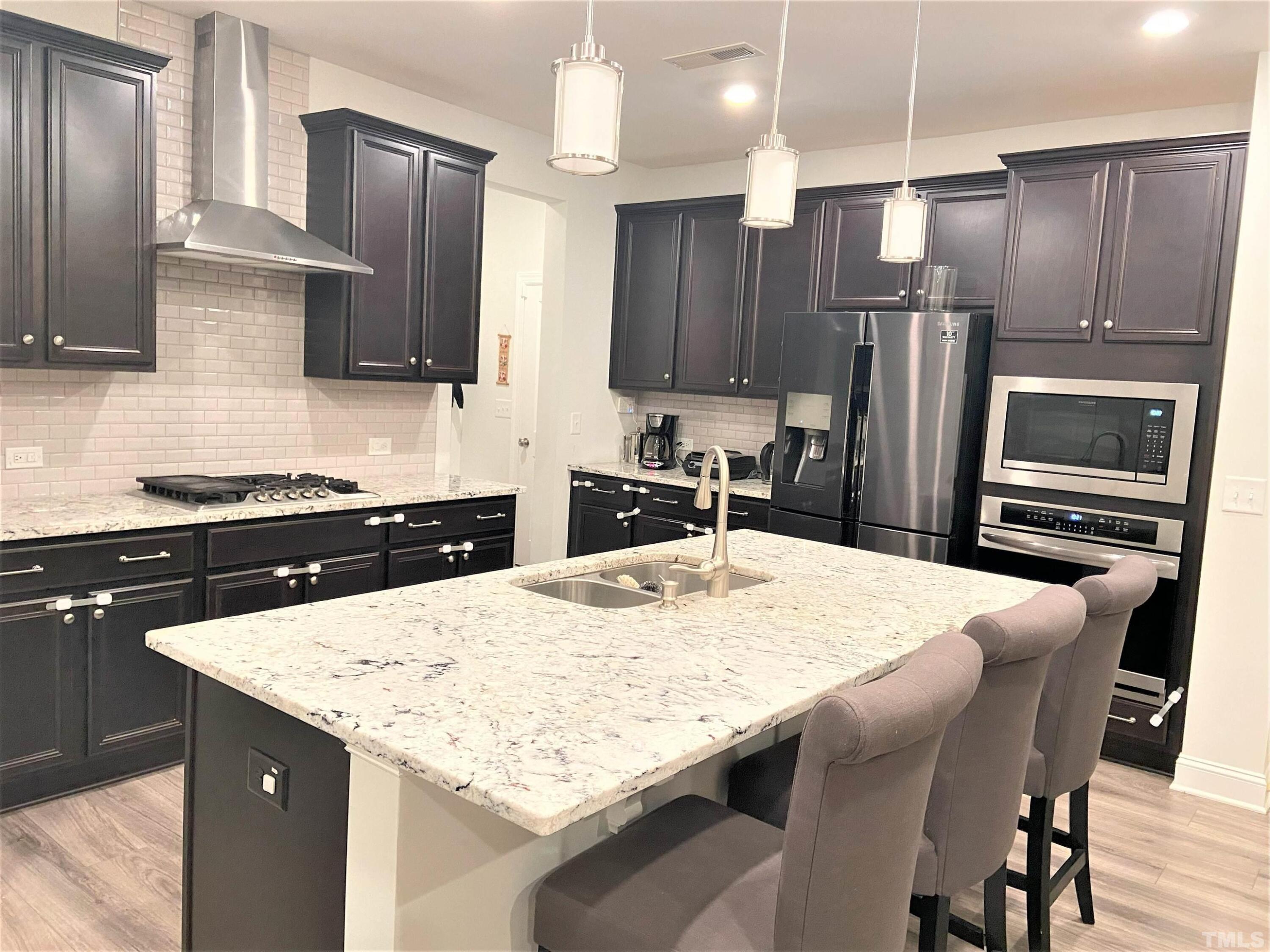 1010 Hero Place Cary, NC 27519 - Photo 6 of 14 a kitchen with stainless steel appliances kitchen island a table chairs sink and cabinets