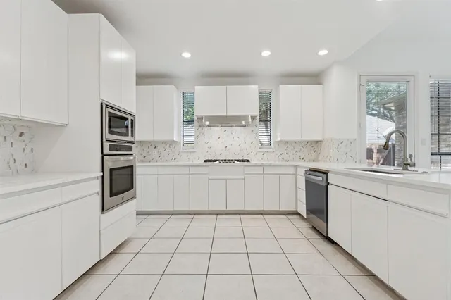 a kitchen with granite countertop white cabinets and white stainless steel appliances