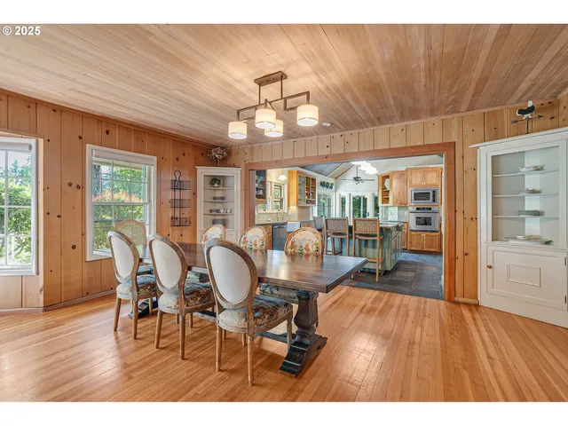 a dining room with wooden floor a chandelier a wooden table and chairs