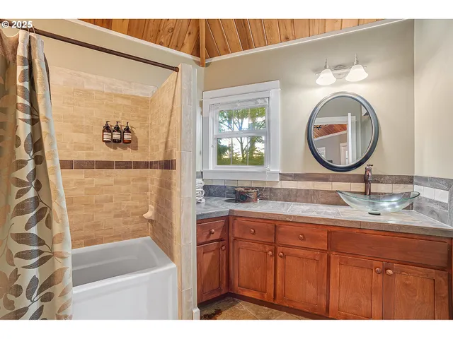 a bathroom with a granite countertop sink a mirror and a shower