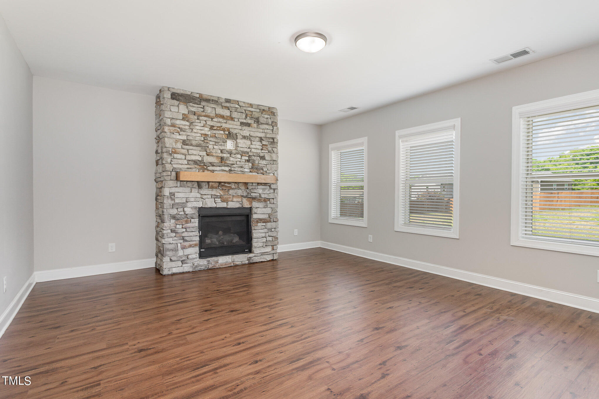 1021 Silver Farm Road Raleigh, NC 27603 - Photo 11 of 42 an empty room with wooden floor fireplace and windows