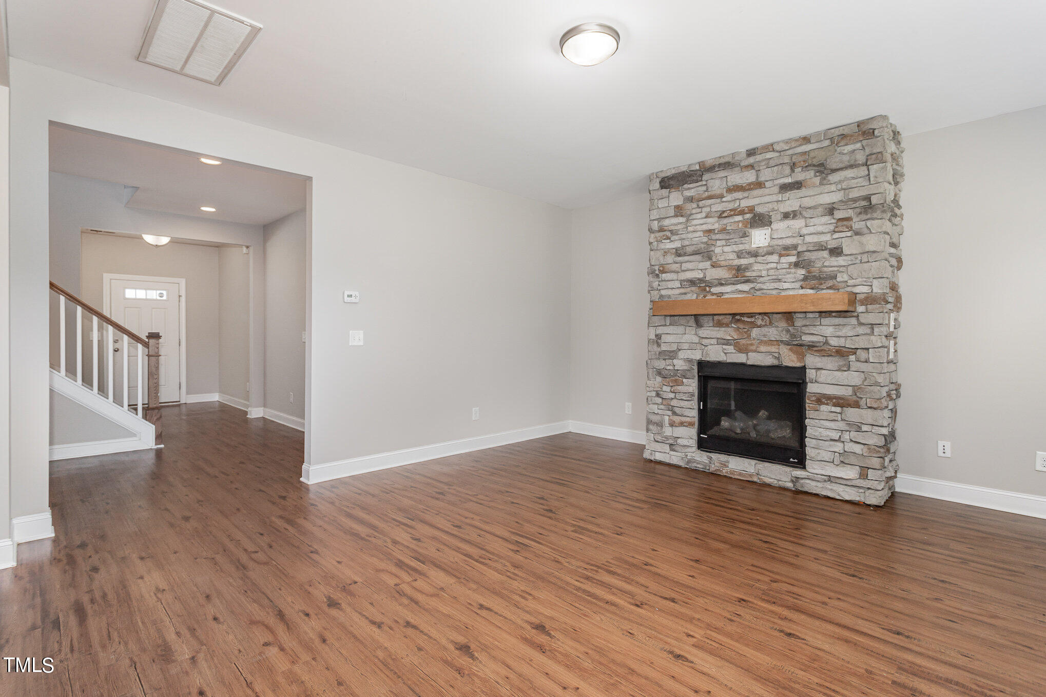 1021 Silver Farm Road Raleigh, NC 27603 - Photo 10 of 42 an empty room with wooden floor a fireplace and windows