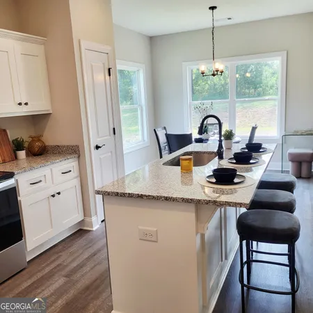 a kitchen with kitchen island granite countertop a stove a sink a dining table and chairs with wooden floor