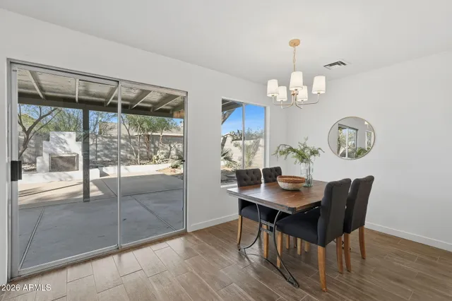 a dining room with wooden floor a chandelier a wooden table and chairs
