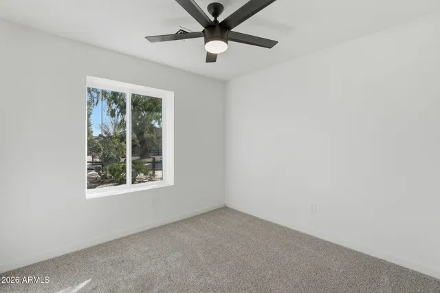 an empty room with a window and a fan