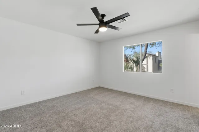 an empty room with ceiling fan and window