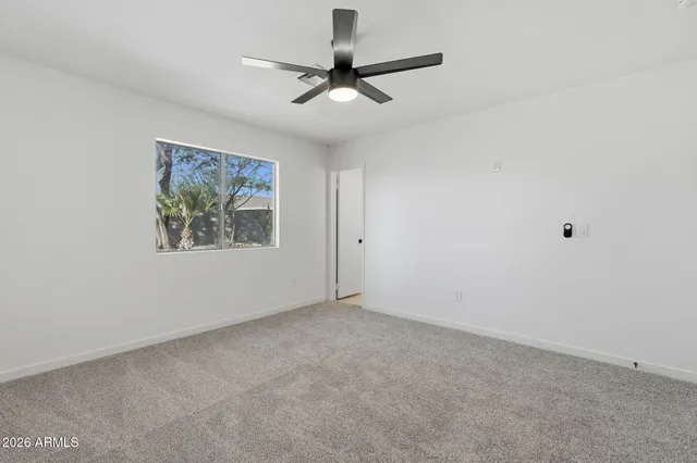 an empty room with a ceiling fan and window