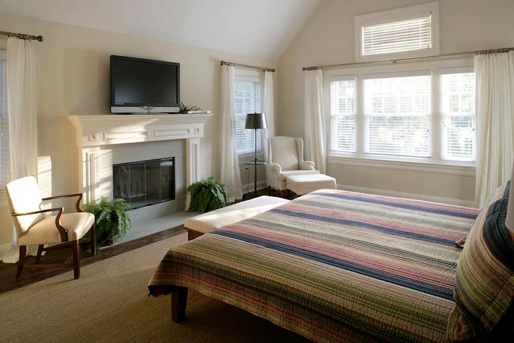 Undisclosed Address Quogue, NY 11959 - Photo 6 of 19 a bedroom with a bed a flat screen tv and a fireplace