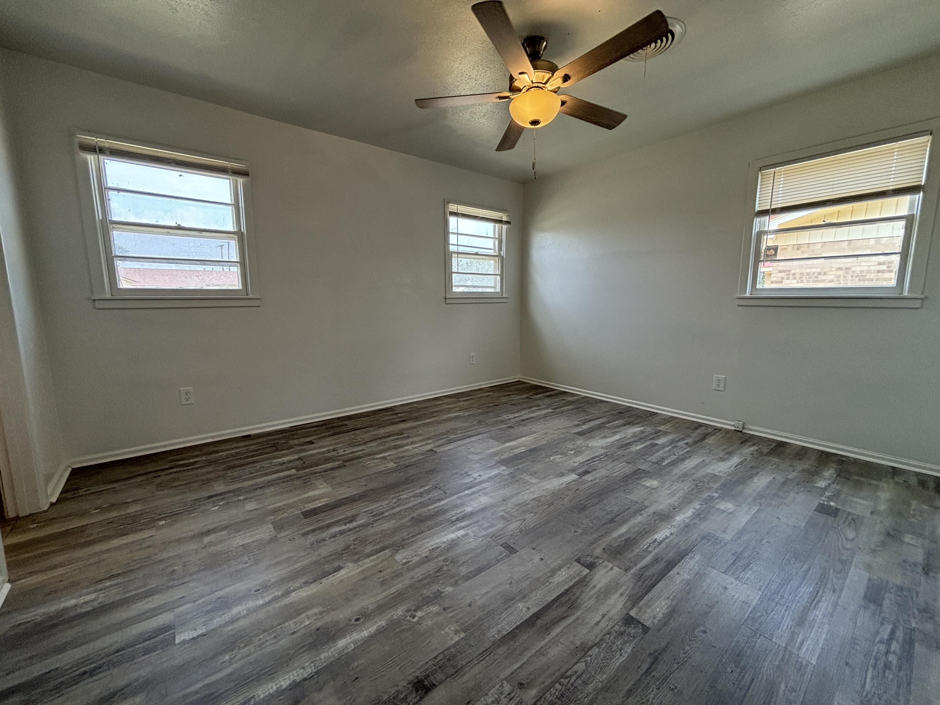 1303 46th Street Lubbock, TX 79412 - Photo 10 of 13 a view of an empty room with a window and wooden floor