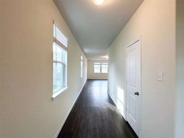 a view of a hallway with wooden floor and windows