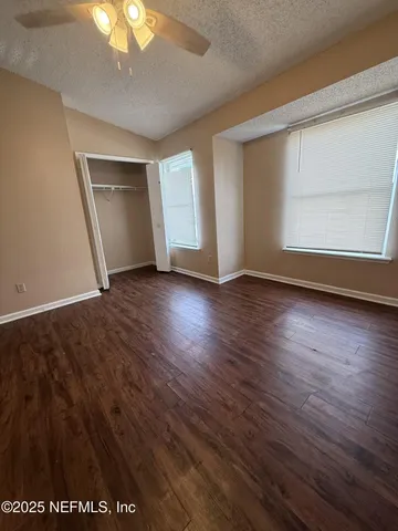 an empty room with wooden floor cabinet and windows