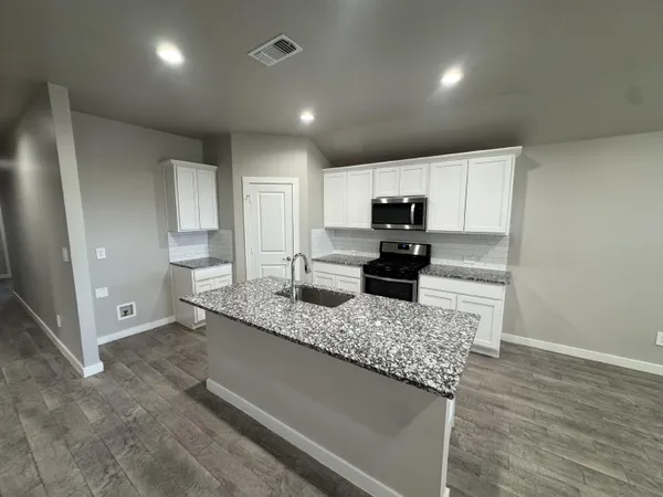 a kitchen with granite countertop stainless steel appliances a sink a counter top space and cabinets