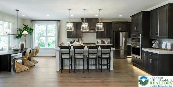 a kitchen with stainless steel appliances kitchen island granite countertop a dining table chairs and a refrigerator