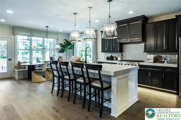 a kitchen with stainless steel appliances granite countertop a stove top oven a sink a dining table and chairs with wooden floor