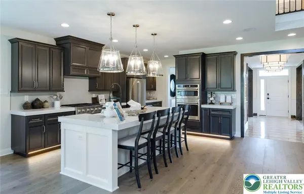 a kitchen with stainless steel appliances kitchen island granite countertop a refrigerator a stove a sink a dining table and chairs with wooden floor